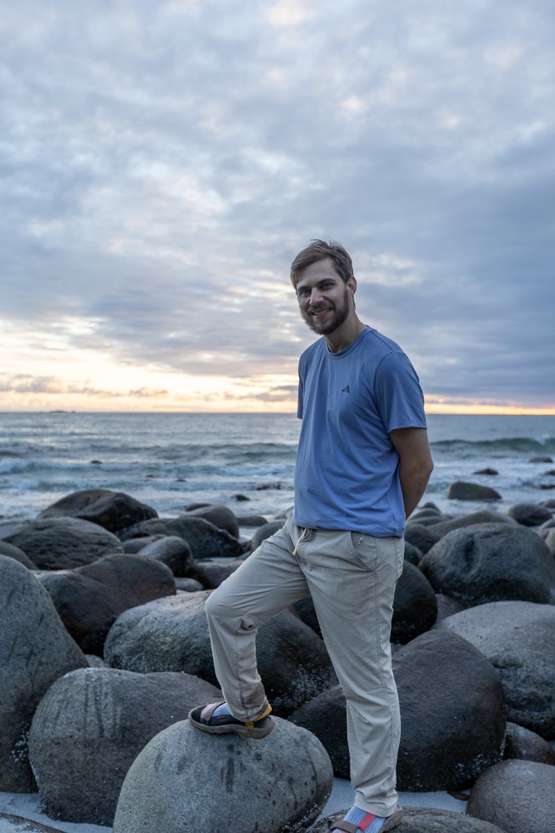Man standing on a rocky shoreline at dusk